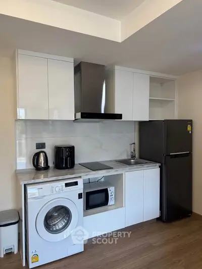 Modern kitchen with sleek appliances and washing machine in compact layout
