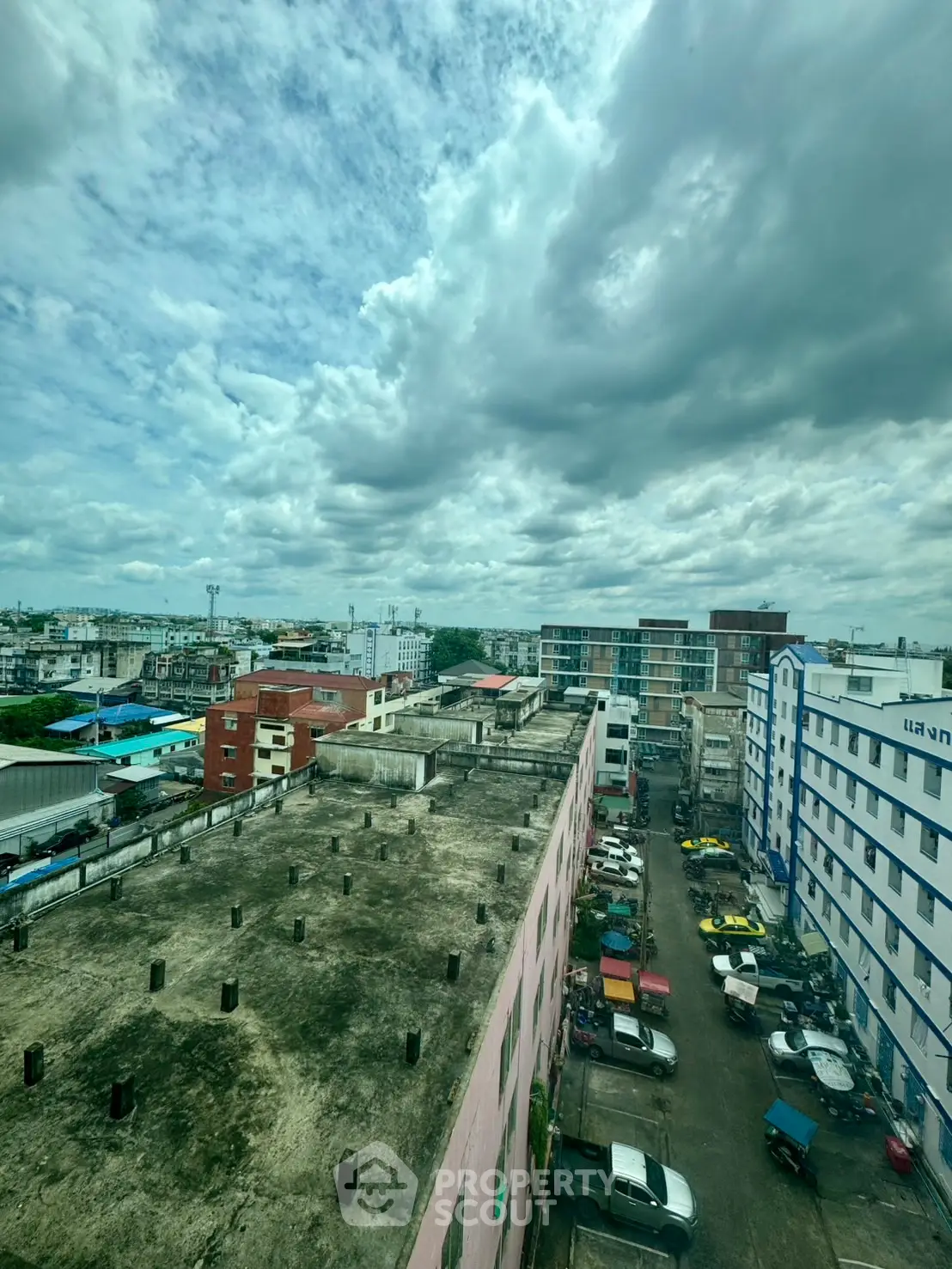 Panoramic cityscape view showcasing urban buildings under a dramatic cloudy sky.