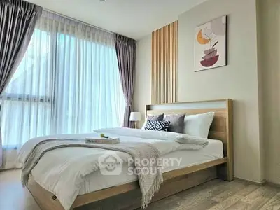 Modern bedroom with stylish decor and natural light, featuring a cozy bed and elegant curtains.
