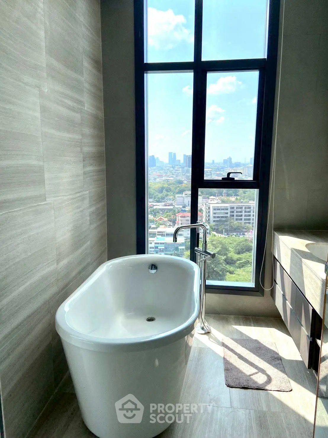 Luxurious bathroom with freestanding tub and stunning city view through large window.