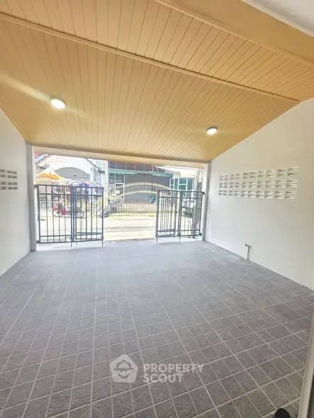 Spacious covered parking area with modern tiled flooring and secure gate access.