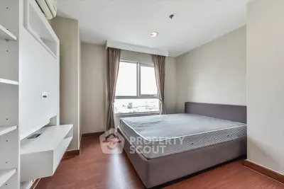 Spacious bedroom with large window and modern furnishings in a stylish apartment.