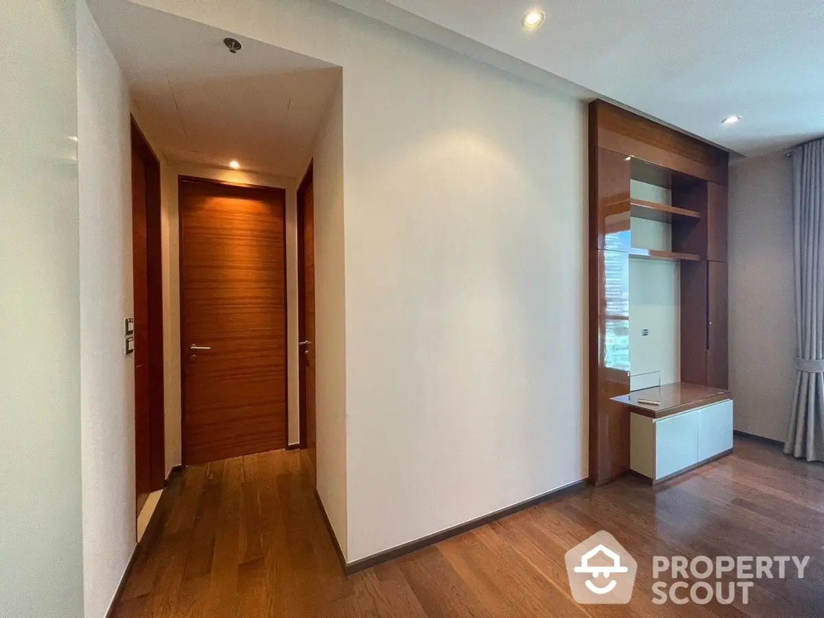 Elegant and modern living space featuring polished hardwood floors, a warm color palette, and sleek built-in shelving, perfect for urban living.