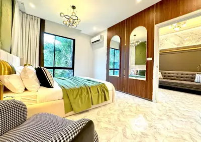 Luxurious bedroom with modern decor and large windows offering lush garden views.