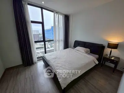 Modern bedroom with large window and city view, featuring stylish decor and cozy ambiance.