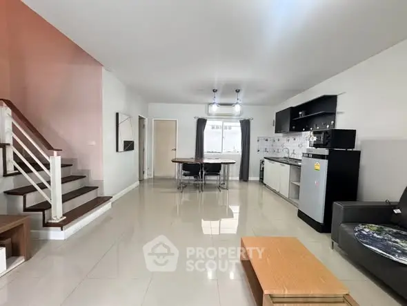 Spacious open-plan living room with modern kitchen and dining area, featuring sleek design and ample natural light.