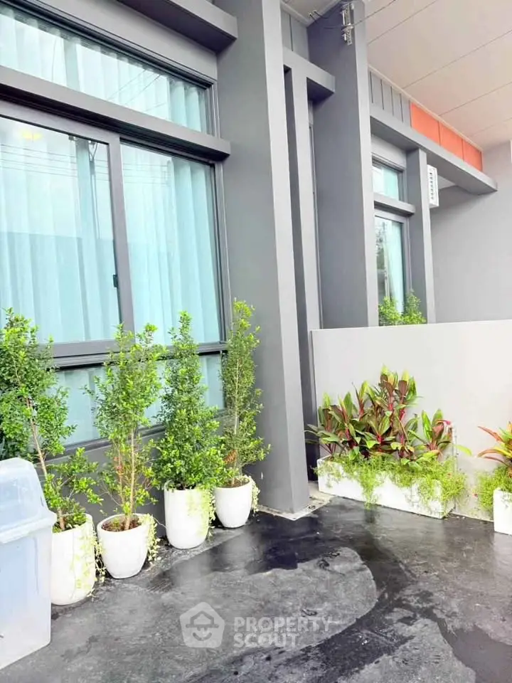 Modern building exterior with potted plants and sleek design.