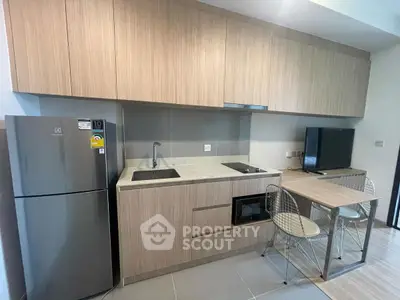 Modern kitchen with sleek cabinetry, compact dining area, and integrated appliances in a stylish apartment.