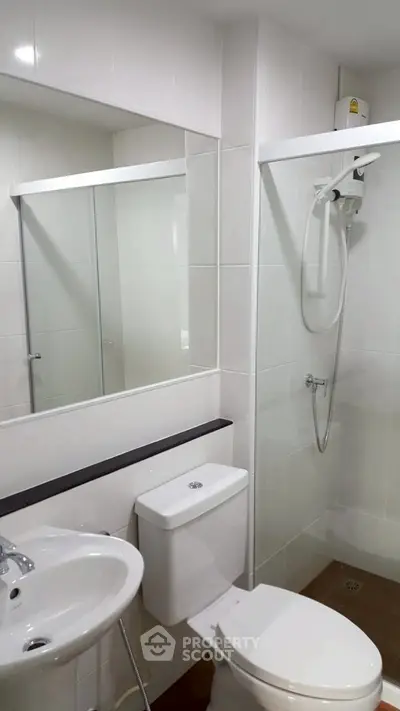 Modern bathroom with shower, toilet, and sink in a sleek white design.