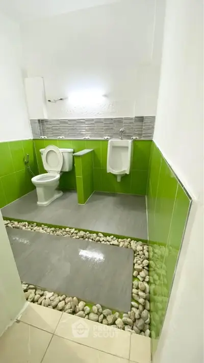 Modern bathroom with green tiles and unique stone flooring design.