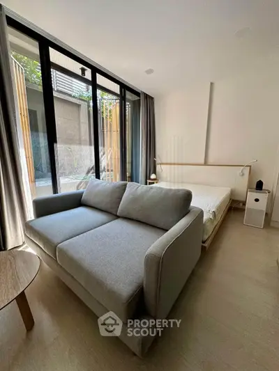 Modern living room with large windows and cozy sofa in stylish apartment