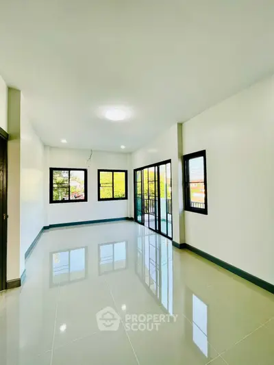 Spacious and bright living room with large windows and glossy tiled floors, perfect for modern living.