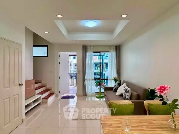 Modern living room with stylish decor and natural light, featuring a cozy sofa and elegant ceiling design.