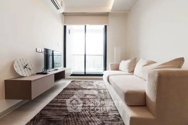 Modern living room with sleek furniture and large window leading to a balcony, offering a bright and airy atmosphere.