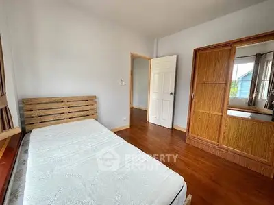 Cozy bedroom with wooden flooring and built-in wardrobe, perfect for relaxation.