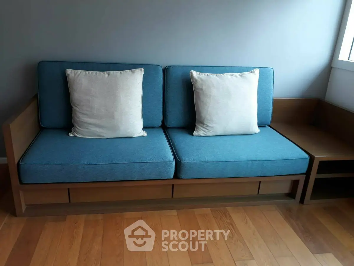 Stylish modern living room with blue sofa and wooden flooring, perfect for cozy relaxation.