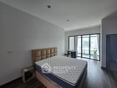 Spacious bedroom with modern decor and large window offering natural light and balcony access.