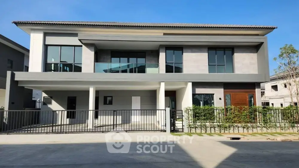 Modern two-story house with sleek design and spacious balcony in a sunny neighborhood.