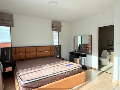 Spacious bedroom with modern decor and ensuite bathroom, featuring natural light and elegant furnishings.