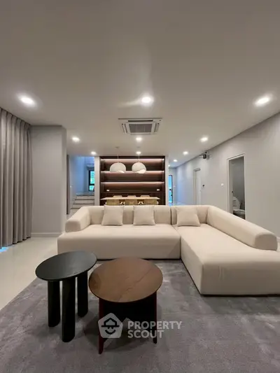 Spacious modern living room with elegant L-shaped sofa and stylish coffee tables, perfect for relaxation and entertainment.