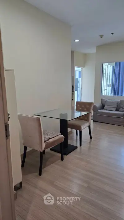 Modern apartment interior with cozy living area and dining set, featuring wooden flooring and neutral tones.