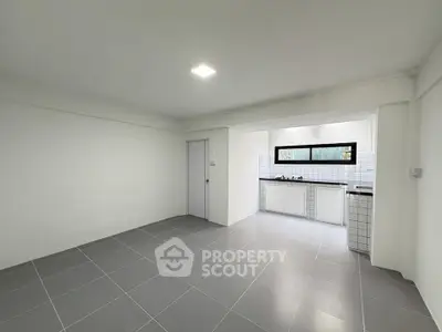 Spacious open-plan kitchen and living area with modern tiled flooring and ample natural light.