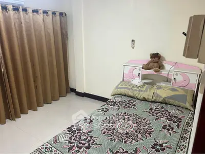 Cozy bedroom with single bed, floral bedding, and teddy bear decor, perfect for a peaceful retreat.