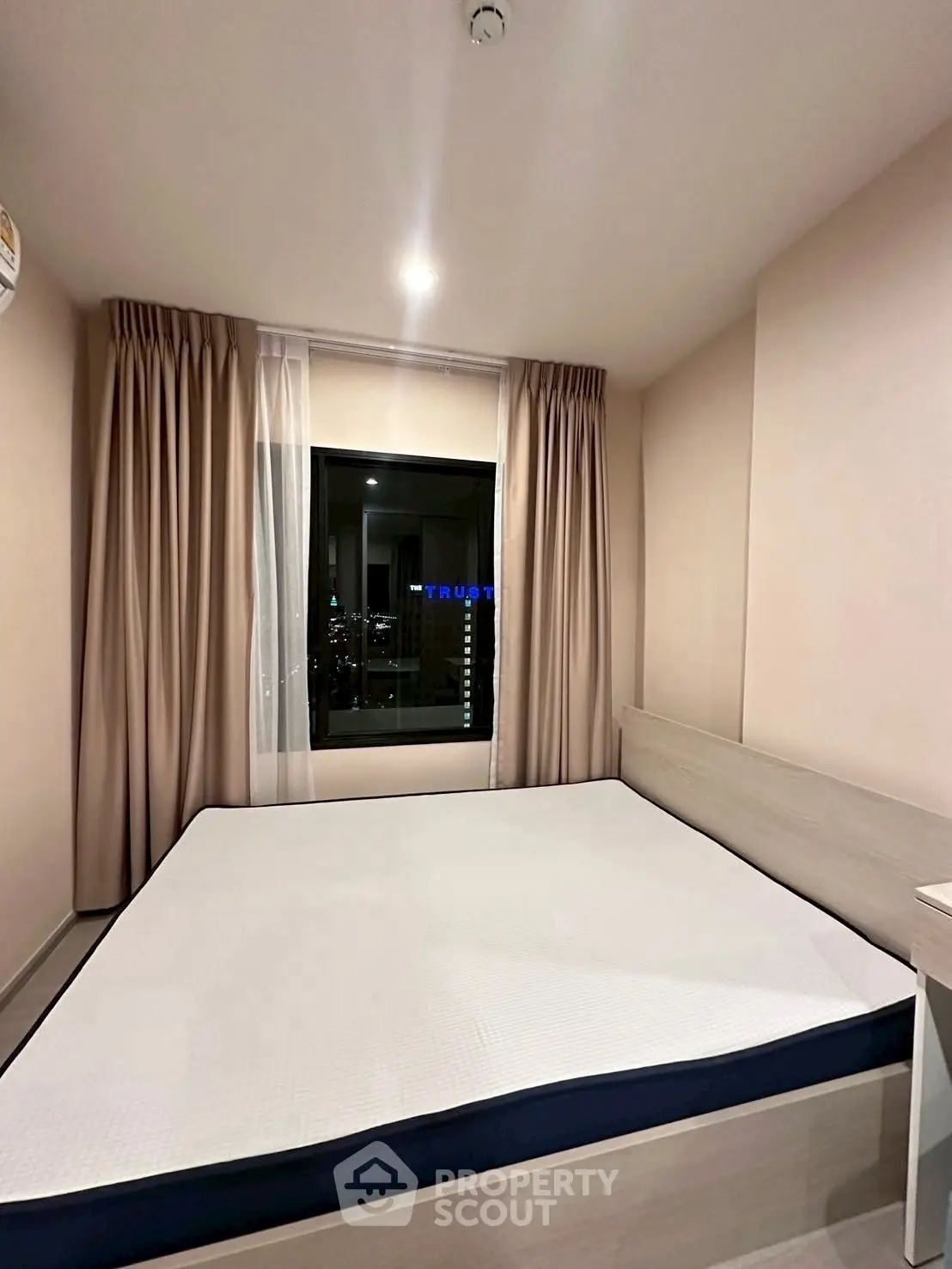 Cozy bedroom with city view, featuring a comfortable bed and elegant curtains.