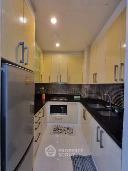 Modern kitchen with sleek cabinetry and black countertops in a compact layout.