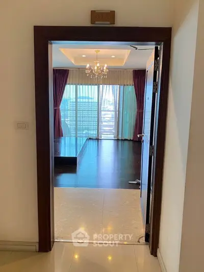 Elegant entrance to a spacious living room with chandelier and large windows.