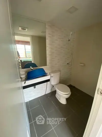 Modern bathroom with sleek design and large mirror, featuring a shower and toilet in a compact space.
