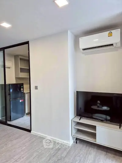 Modern living room with sleek TV setup and air conditioning in a stylish apartment.
