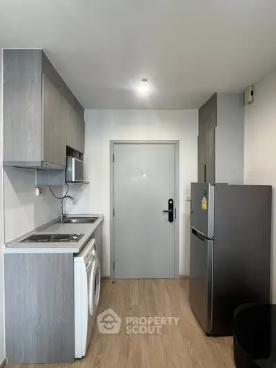 Modern compact kitchen with sleek appliances and wooden flooring