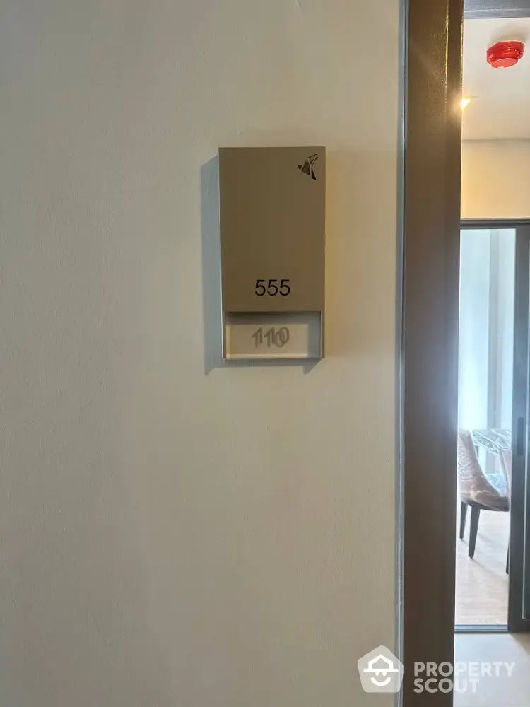 Modern apartment entrance with room number 555 and stylish interior glimpse.