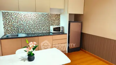 Modern kitchen with mosaic backsplash and sleek appliances in cozy apartment.