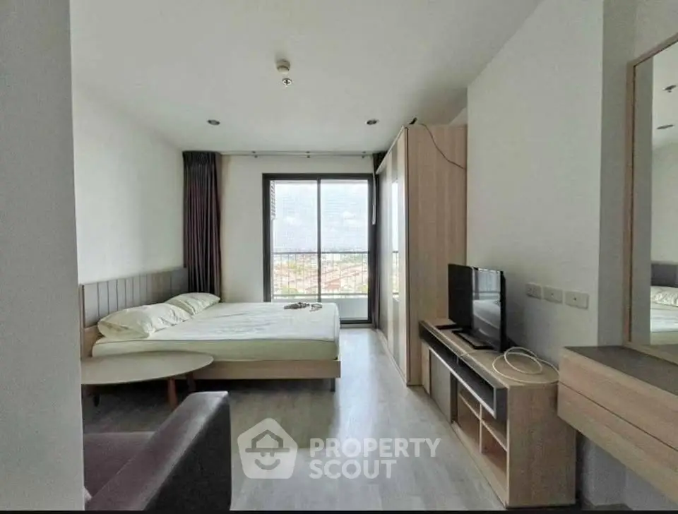 Modern bedroom with large window and city view, featuring a cozy bed and sleek furniture.