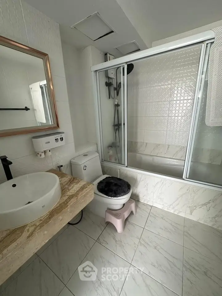 Modern bathroom with elegant marble flooring and stylish fixtures, featuring a glass-enclosed bathtub and sleek vanity.