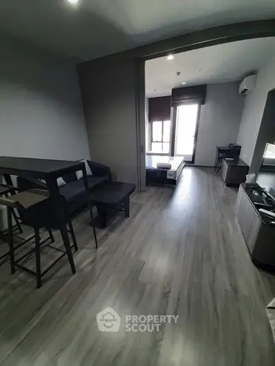 Modern studio apartment with sleek flooring and minimalist furniture, featuring a cozy living area and bedroom.