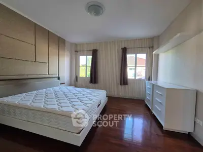 Spacious bedroom with large windows and modern furnishings in a well-lit home.