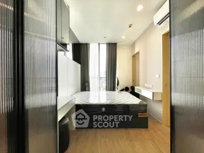 Modern bedroom with sleek design and large window offering city view, featuring built-in storage and air conditioning.