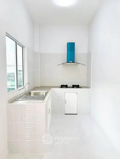 Modern minimalist kitchen with sleek white tiles and gas stove