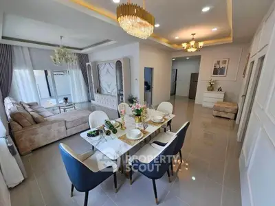 Elegant open living and dining area with luxurious chandelier and modern furniture