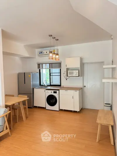 Modern kitchen with washing machine and dining area in cozy apartment