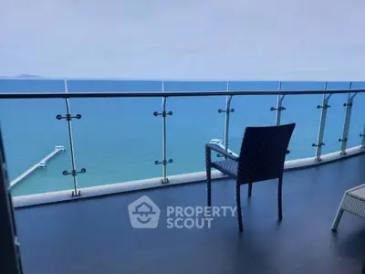 Stunning ocean view from modern balcony with glass railing and seating.