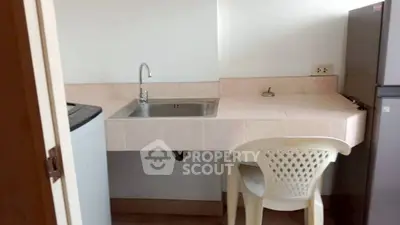 Compact kitchen area with sink, washing machine, and fridge in a minimalist design.