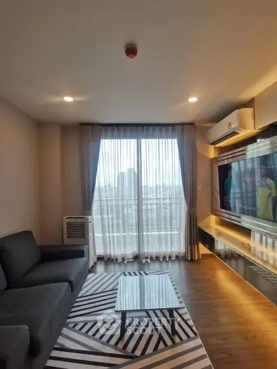 Modern living room with stylish decor and city view, featuring a sleek sofa and large TV.