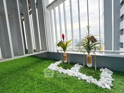 Charming balcony with artificial grass and decorative plants offering a serene city view.