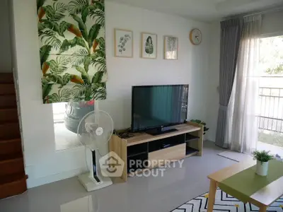 Modern living room with TV, stylish decor, and natural light.