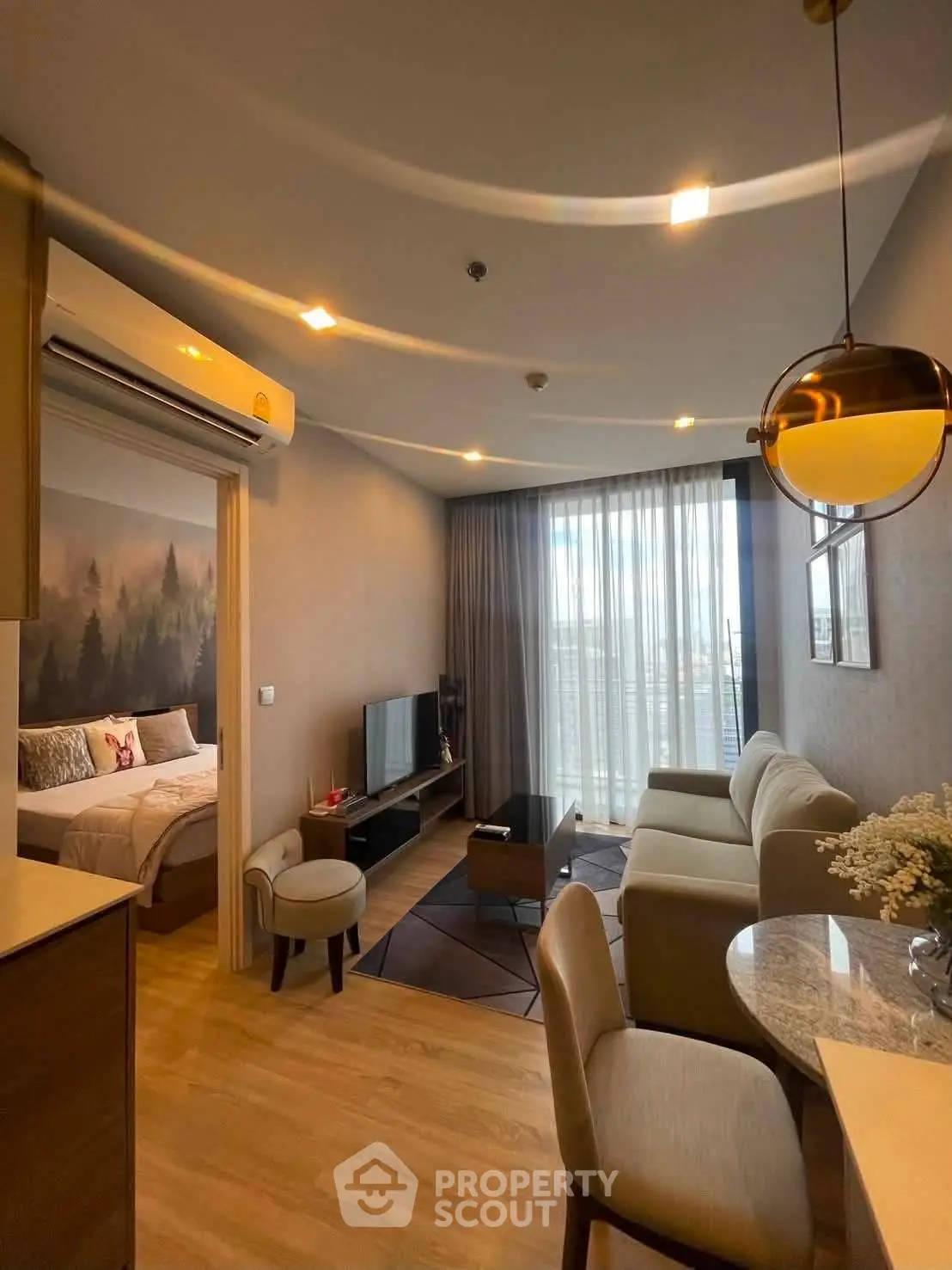 Modern open-plan living room with cozy seating and natural light, adjacent to a stylish bedroom.