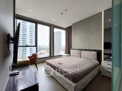 Modern bedroom with large windows offering stunning city views in a high-rise apartment.